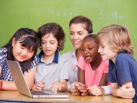 Interracial primary classroom learning to use laptop with their