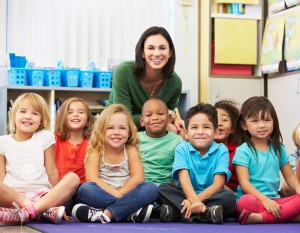 Preschool teacher sits with seven small children.