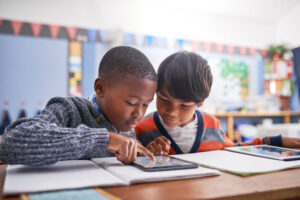 Two boys figuring out schoolwork together in classroom