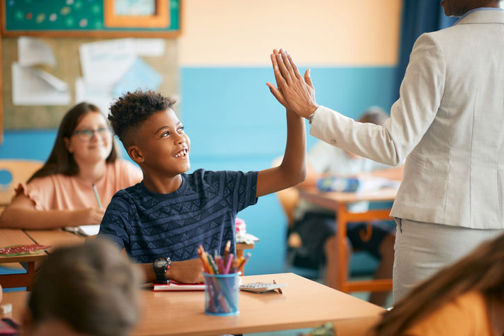 teacher high fiving student in classroom