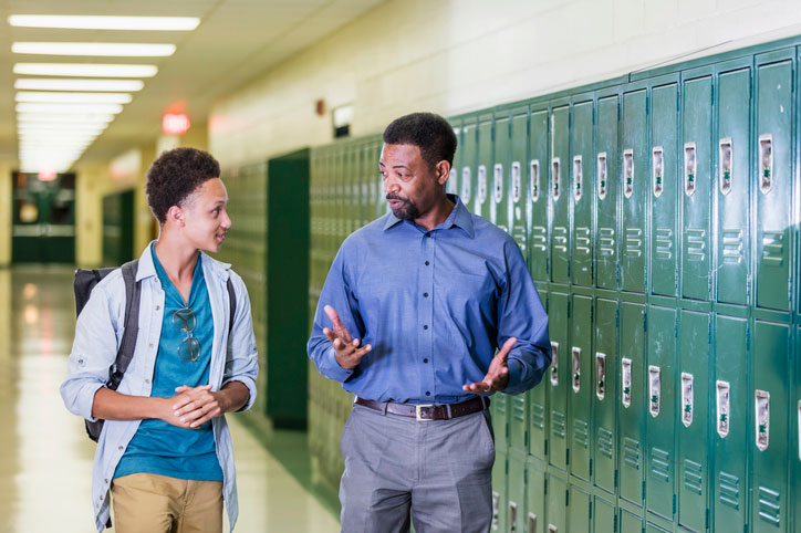 teacher talking to student in the high school hallway