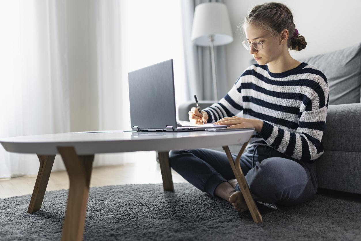 A teenage girl attends online classes at home during the COVID-19 pandemic, emphasizing the impact of education policies on teaching degree programs.