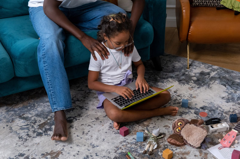 young girl on laptop at home with dad helping