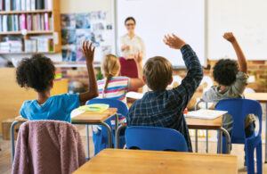 classroom of kids raising their hands